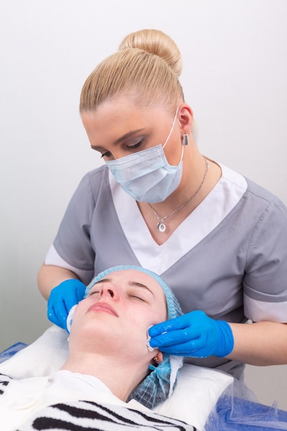 La cosmetóloga trata la piel de la cara con un tónico.