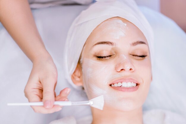 Cosmetologia Closeup da mão do cosmetologista aplica máscara facial de limpeza com um pincel
