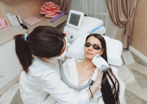 Cosmetologia Linda mulher recebendo procedimento de depilação a laser no salão de beleza Closeup das mãos de uma esteticista fazendo procedimentos cosméticos para o rosto de uma mulher em um salão de spa
