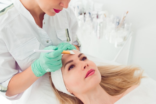 Cosmetologia procedimento de beleza Cuidados com a pele de mulher jovem usando uma escova para hidratar o rosto