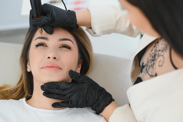 Cosmetologista aplicando maquiagem permanente na tatuagem de sobrancelha de sobrancelhas