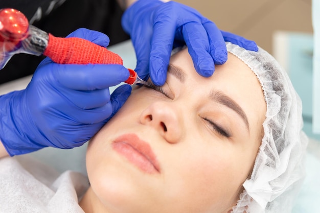 Cosmetologista aplicando maquiagem permanente nas sobrancelhas - tatuagem de sobrancelha.