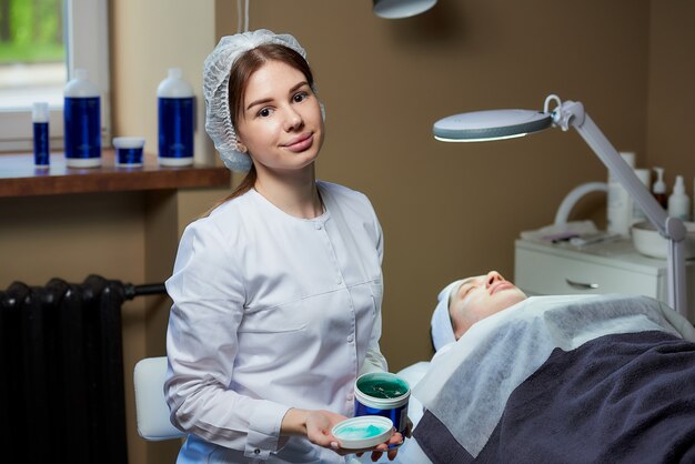 Cosmetologista com um gel para a pele perto do paciente na cama de beleza totalmente elétrica