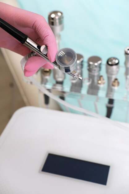 Foto cosmetologista de mão segurando a máquina de cuidados com a pele