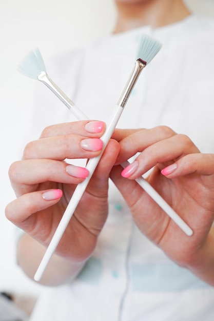 Foto cosmetologista em equipamento médico segurando duas escovas cosmológicas