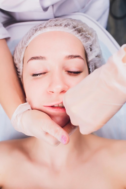 cosmetologista faz uma massagem bucal dos músculos faciais do paciente