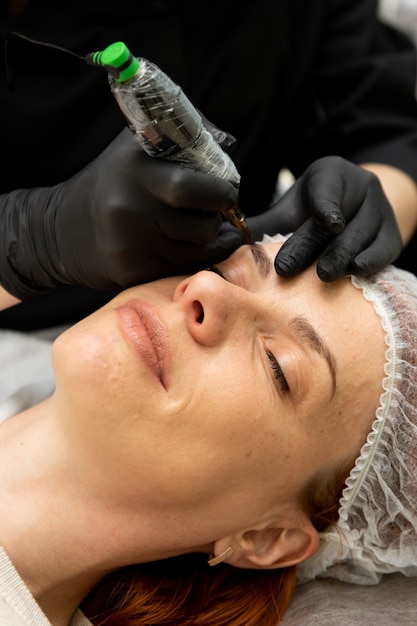 Cosmetologista fazendo maquiagem definitiva para sobrancelhas