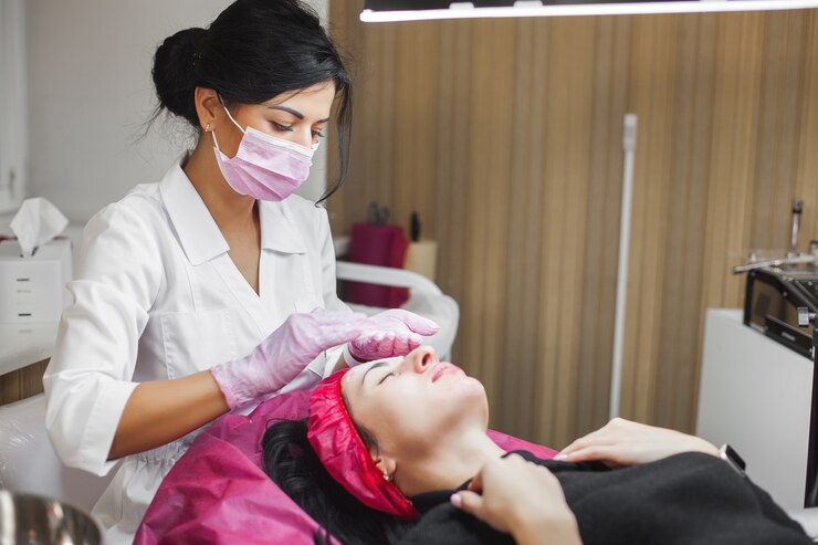 Cosmetologista fazendo uma massagem de rosto para seu paciente e uma máscara facial. Procedimento antienvelhecimento em um salão de beleza.