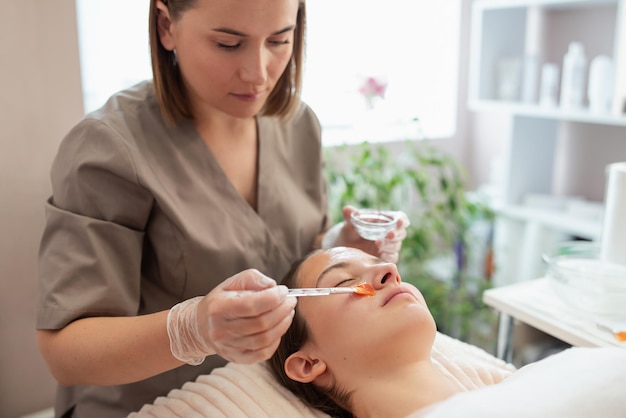 Foto cosmetologista feminina colocando gel para hidrogenação a frio antes do procedimento de limpeza no rosto afrouxamento e separação do estrato córneo abertura dos poros hidratando e suavizando a pele