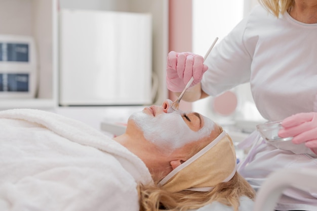 Cosmetologista feminina faz procedimentos faciais para clínica de clientes em estética