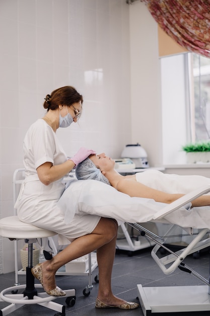 Foto cosmetologista no escritório fazer procedimentos para a menina