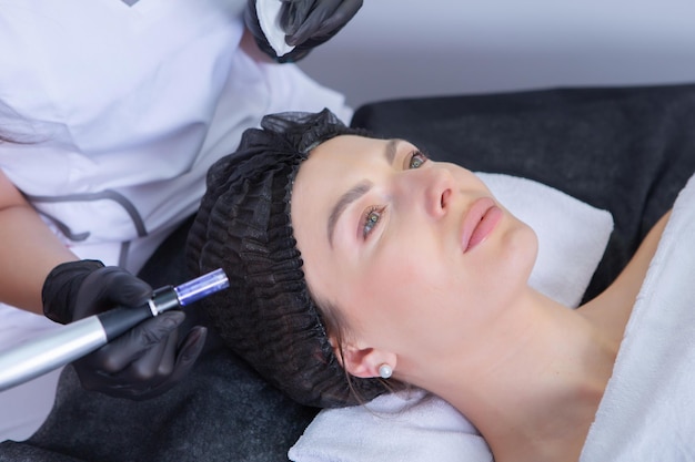 Cosmetologista profissional a fazer massagem facial a uma mulher num salão de spa.