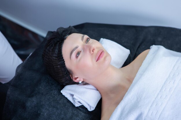 Cosmetologista profissional a fazer massagem facial a uma mulher num salão de spa.