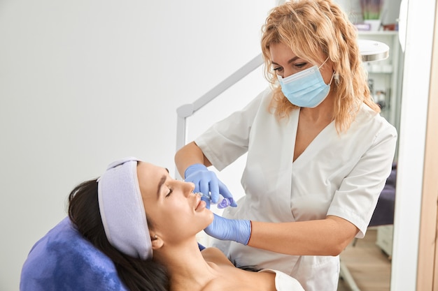 Cosmetologista profissional está realizando procedimentos para o cliente no gabinete