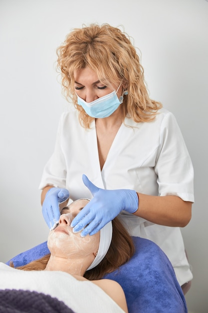 Cosmetologista profissional está realizando procedimentos para o cliente no gabinete