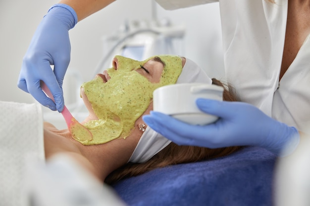 Foto cosmetologista profissional está realizando procedimentos para o cliente no gabinete