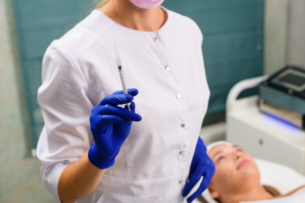 Cosmetologista profissional prepara seringa para injeção