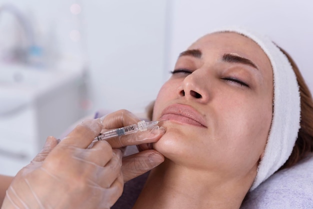 Cosmetologista realiza injeções de preenchimento labial com preenchimento de ácido hialurônico no rosto de uma mulher Cosmetologia estética feminina em um procedimento de aumento de lábios de salão de beleza