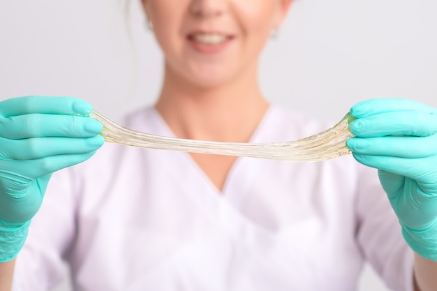 Cosmetologista segura pasta de açúcar ou cera de mel para remoção de cabelo em luvas médicas, close-up.