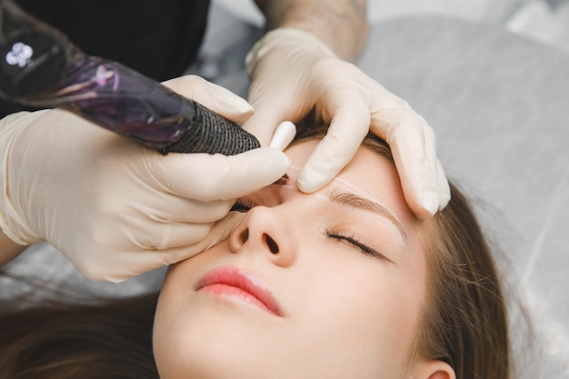 Un cosmetólogo aplica maquillaje permanente a las cejas tatuaje de cejas permanente de cejas