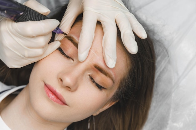 Un cosmetólogo aplica maquillaje permanente a las cejas tatuaje de cejas permanente de cejas
