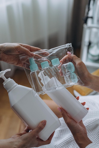 El cosmetólogo muestra al cliente un producto cosmético y botellas de plástico para cosméticos de viaje