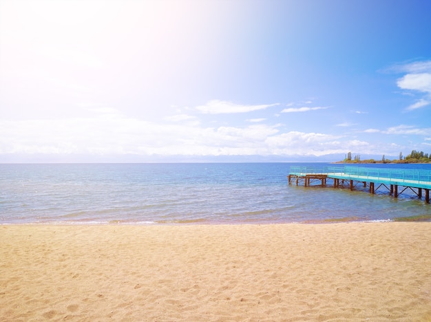 Costa arenosa. oceano calmo. Grande cais. Férias perfeitas