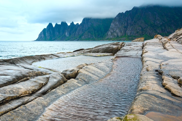 Costa da noite de verão. A rocha dos dentes do dragão, Jagged Ersfjord, Senja, Noruega.