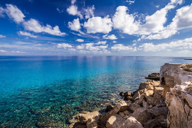 Costa do mar com águas turquesas claras e pedras na capa Cavo Greco.