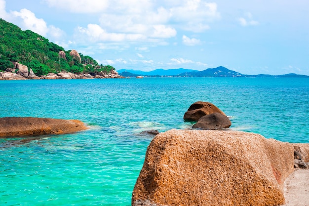 Costa do mar com uma costa rochosa e uma montanha coberta de vegetação Férias na Tailândia em uma ilha tropical