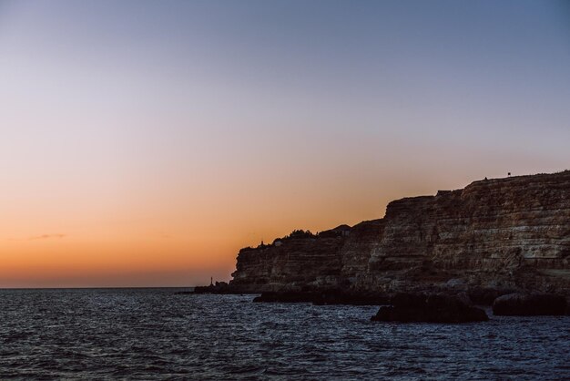 Costa do mar e as rochas acima do mar durante o pôr do sol Bela paisagem do mar