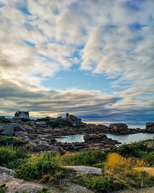 Costa de granito en Bretaña cerca de Ploumanach, Francia. Ploumanach Mean Ruz faro rojo atardecer en la costa de granito rosa, Perros Guirec, Bretaña