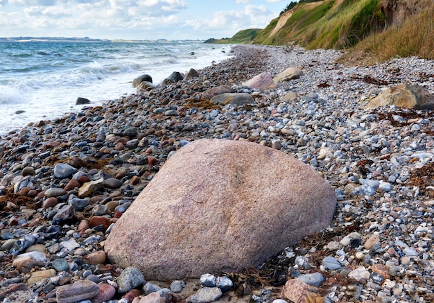 Costa de Kattegat Helgenaes Dinamarca Las olas del océano se lavan en las piedras vacías de la orilla de la playa Paraíso tranquilo y pacífico del paisaje marino y el cielo de verano para unas vacaciones relajantes y divertidas en el extranjero o para viajar de vacaciones