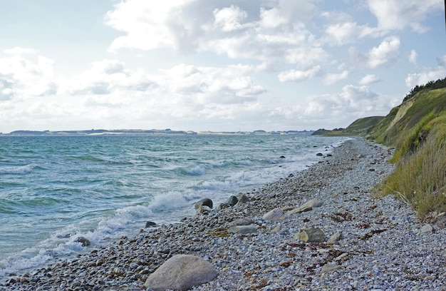 Costa de Kattegat Helgenaes Dinamarca Las olas del océano se lavan en las piedras vacías de la orilla de la playa Paraíso tranquilo y pacífico del paisaje marino y el cielo de verano para unas vacaciones relajantes y divertidas en el extranjero o para viajar de vacaciones