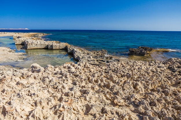 Costa del mar con agua turquesa clara y piedras afiladas.