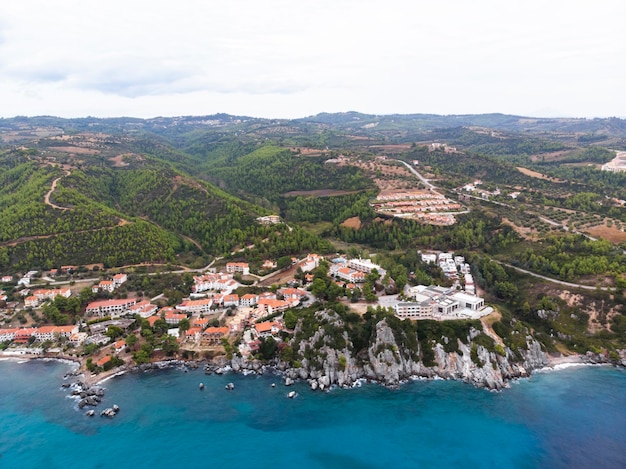 Costa del mar Egeo de Grecia, edificios de Loutra ubicados cerca de los acantilados rocosos, vegetación y agua azul. Vista desde el dron