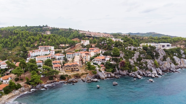 Costa del mar Egeo de Grecia, edificios de Loutra ubicados cerca de los acantilados rocosos, vegetación y agua azul. Vista desde el dron