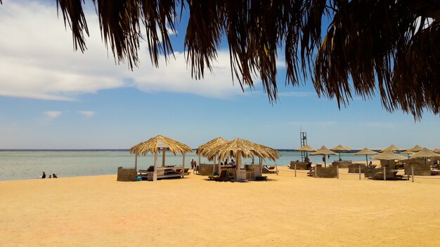 Costa del mar con sombrillas de paja en una playa de arena. Paisaje marino en la playa al final de la temporada navideña. Un gran lugar para relajarse en el Mar Rojo en Sharm El Sheikh, Egipto.