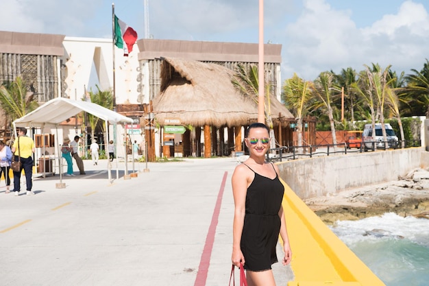 Costa Maya, México - 1 de fevereiro de 2016: mulher de óculos escuros fica no cais no mar em dia ensolarado. Férias de verão, conceito de viagem