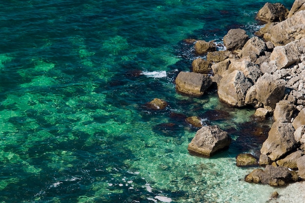 Costa rochosa com água do mar transparente verde-azul