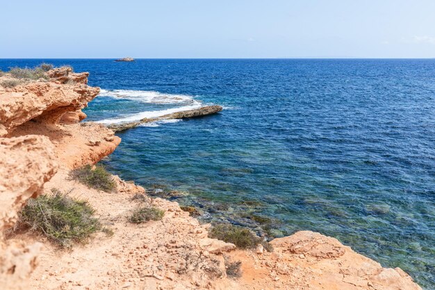 Costa rochosa com plantas raras muda de cor dependendo da profundidade do céu claro Ilhas Baleares de Ibiza