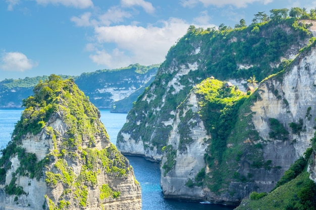 Costa rochosa do oceano da ilha da Indonésia. Várias cabanas no topo de um penhasco entre a floresta tropical