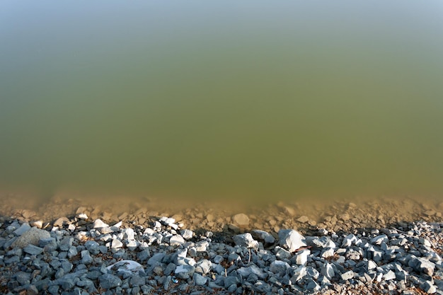 Costa rocosa del río con agua fangosa un lugar para copiar