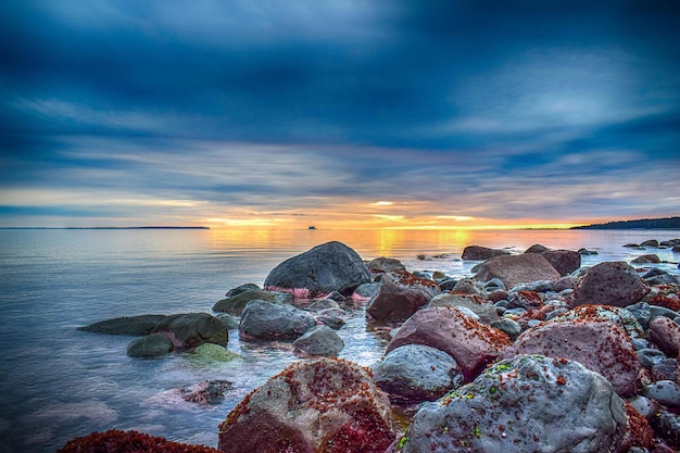 Costa rocosa rodeada por el mar bajo un cielo nublado durante la puesta de sol