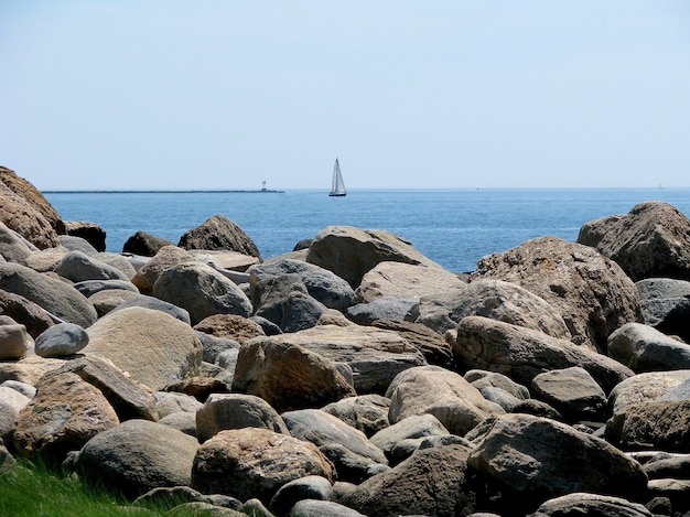 Costa rocosa con velero en el fondo de la costa de Hammonasset Beach State Park