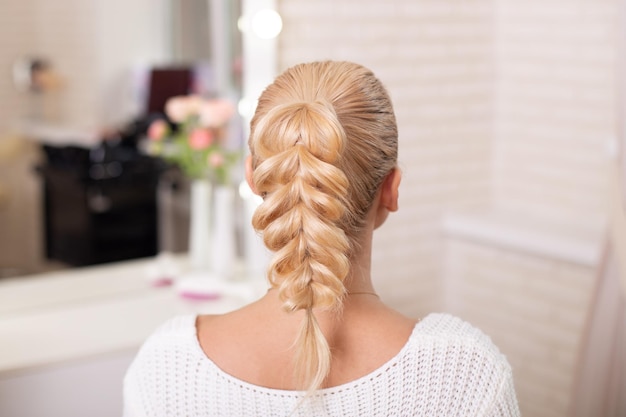 Costas femininas com cabelo louro trançado