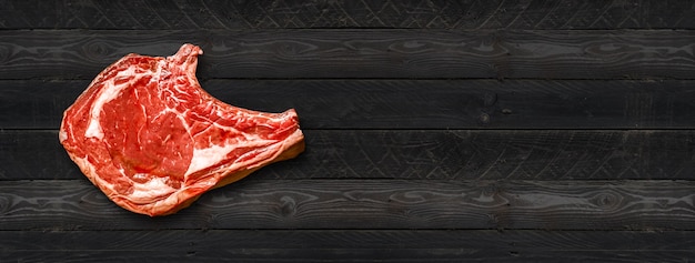 Costela de carne crua isolada em fundo preto de madeira. Vista do topo. Banner horizontal