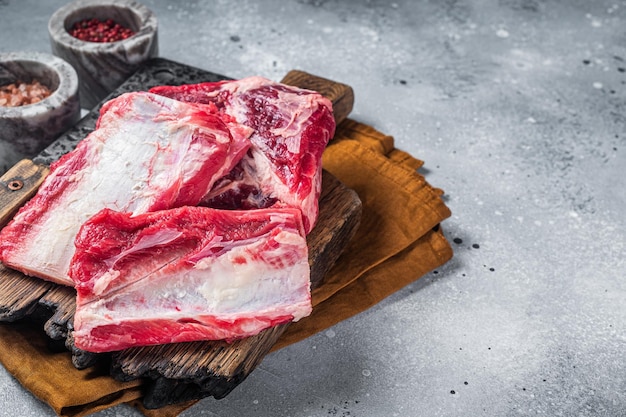 Costelas curtas de vitela kalbi carne crua na tábua de açougueiro de madeira Fundo cinza Vista superior Copiar espaço