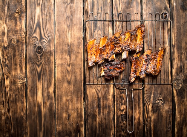 Costelas de churrasco de carne na grelha na mesa de madeira.