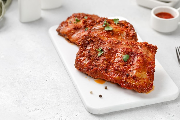 Costelas de churrasco de porco marinadas cozidas na tábua de cerâmica branca e fundo branco Copie o espaço